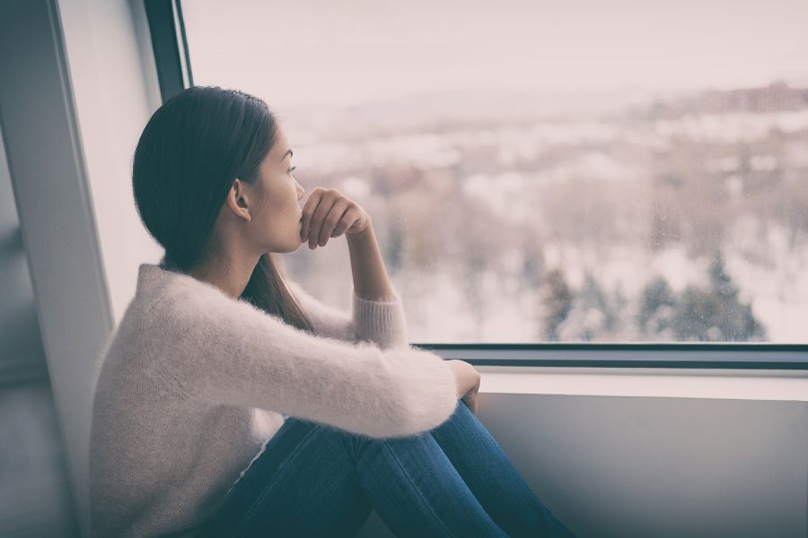 Woman looking out of window, trying to overcome her trust issues