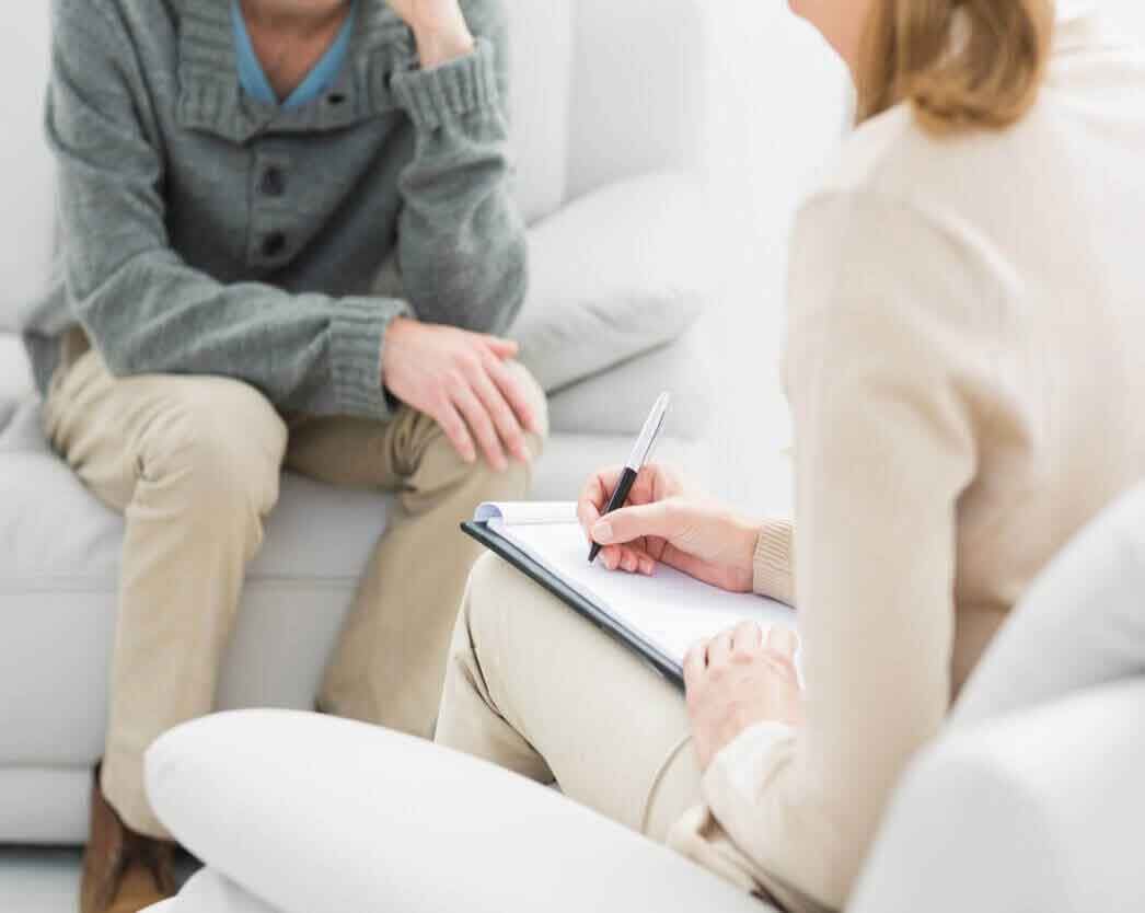 Psychotherapist taking notes while speaking with a client