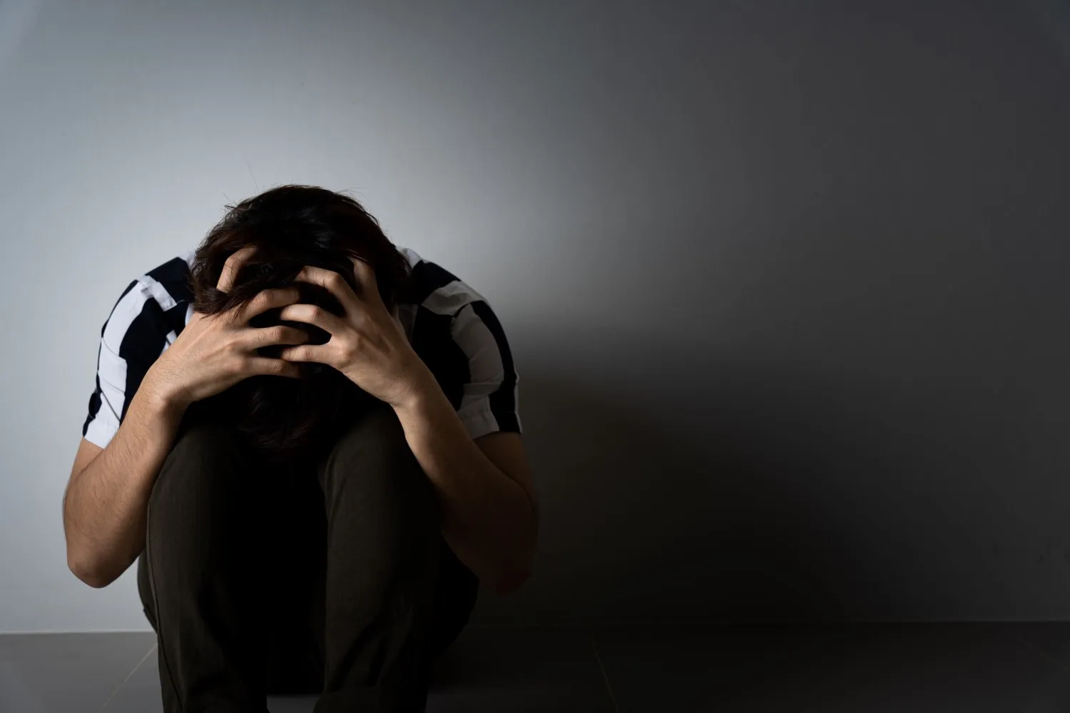 Distressed man sitting on the floor with his head in his hands