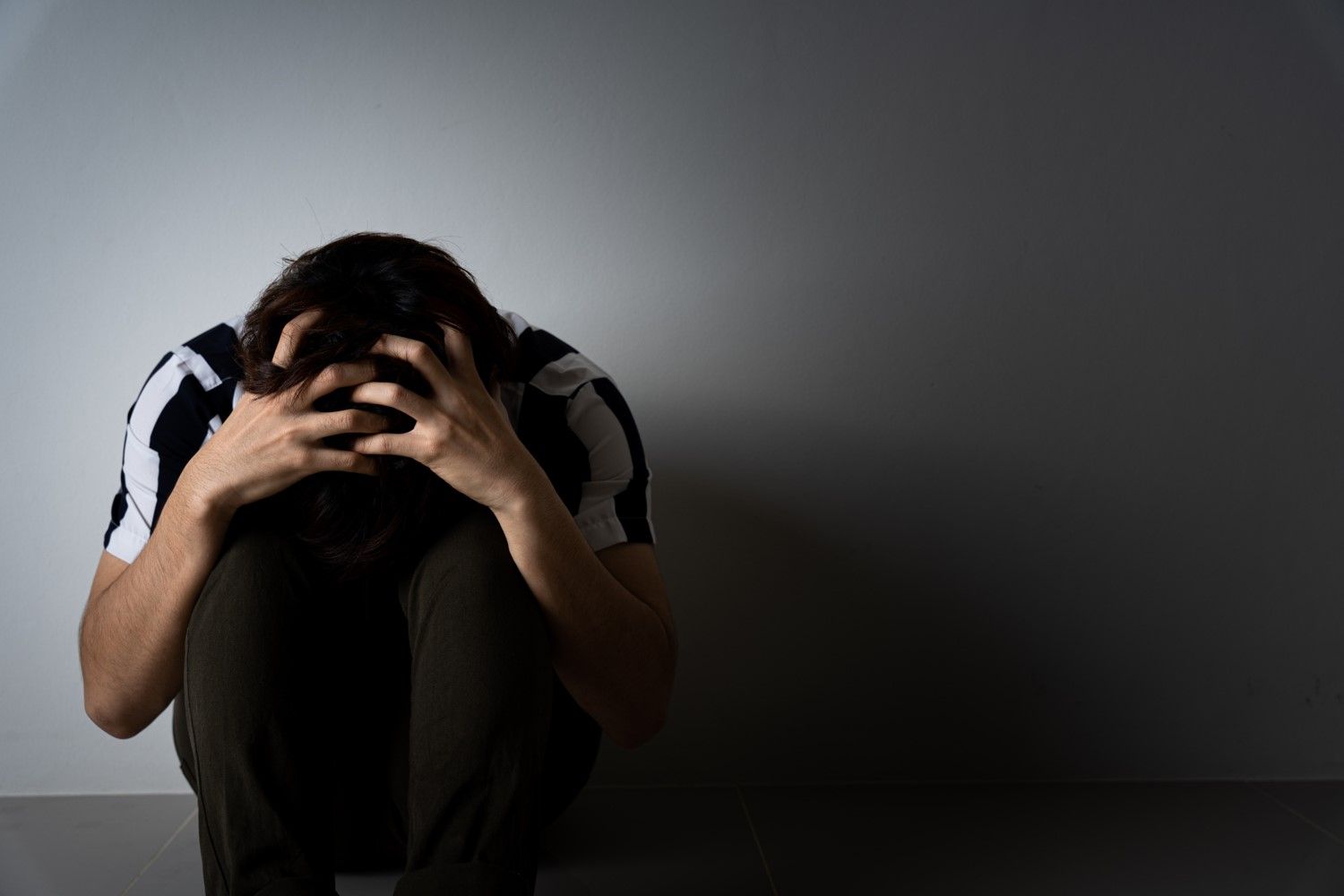 Distressed man sitting on the floor with his head in his hands