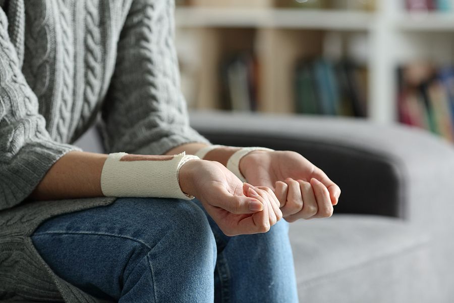 Person gently holding their arm, bandaged from cuts