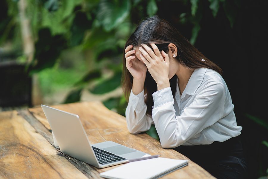 Woman depressed at work sitting infront of laptop