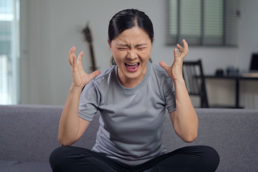 Woman raising her hands and shouting while expressing anger and frustration