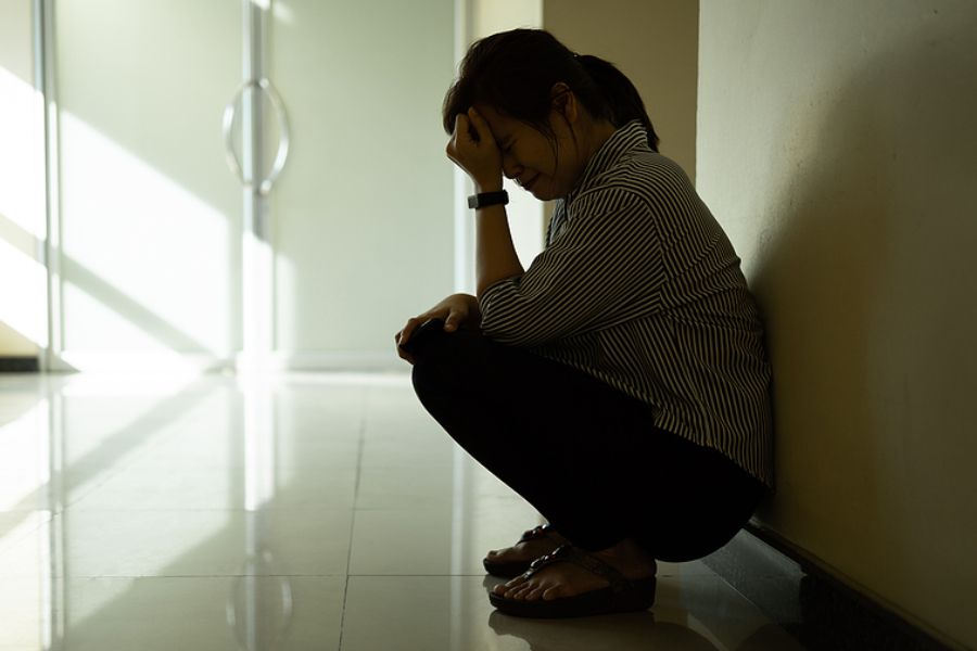 Woman sitting by a corridor feeling hopeless