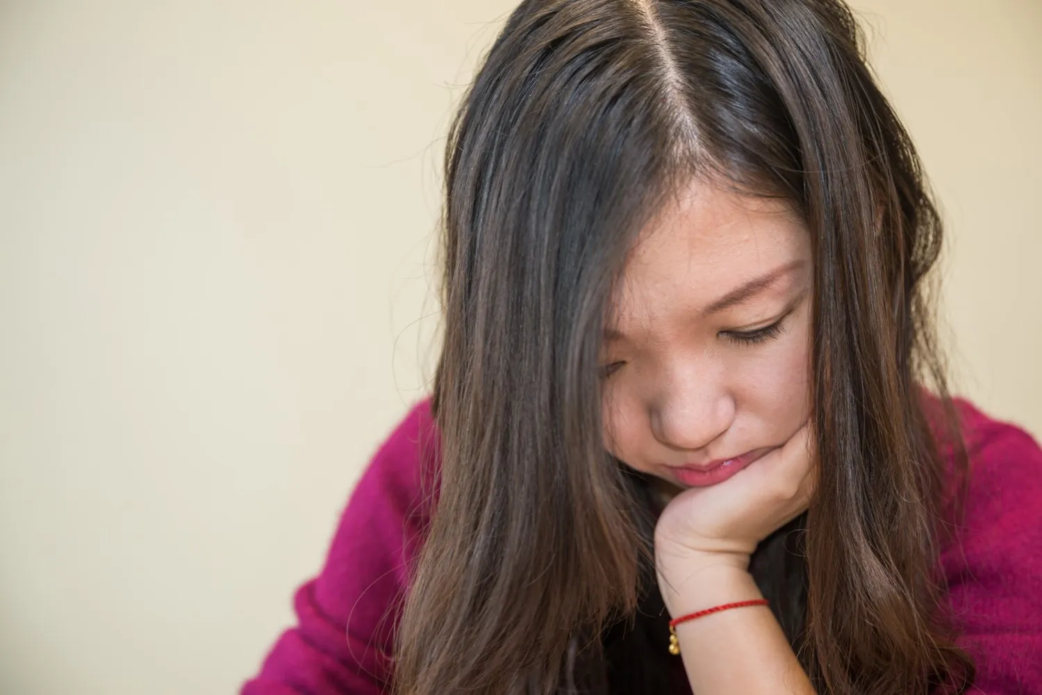 Young woman looking down with her head resting on one hand
