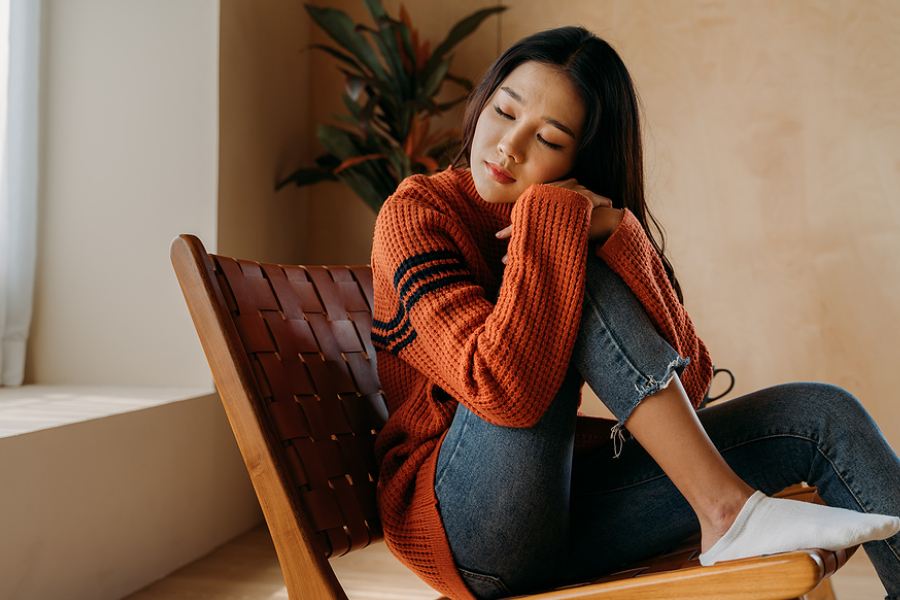 Teen sitting quietly by a window, reflecting on feelings of loneliness