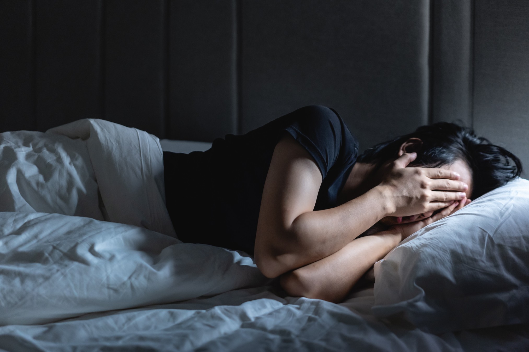 Woman lying on bed covering face having trauma
